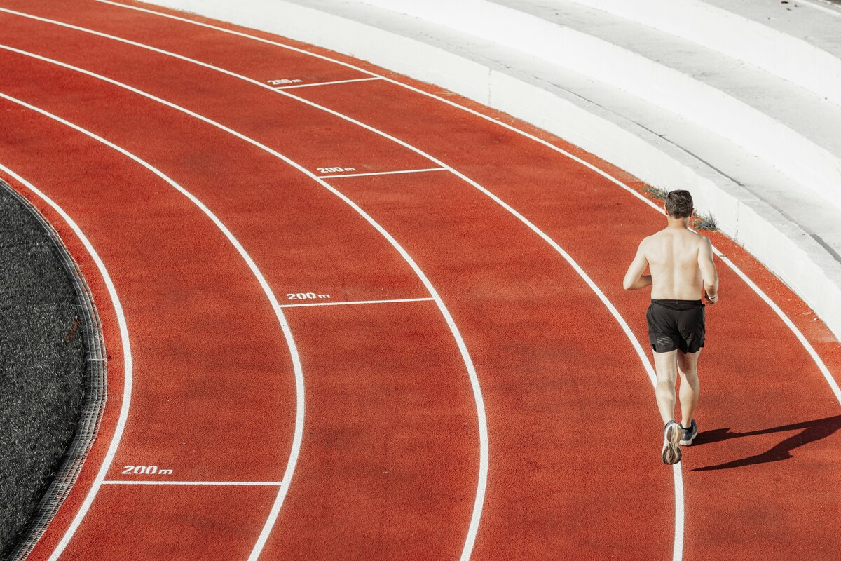 Бегун на красной беговой дорожке — интервальная тренировка на стадионе